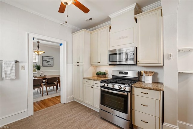kitchen featuring stainless steel appliances, crown molding, a ceiling fan, light wood-style flooring, and light stone countertops