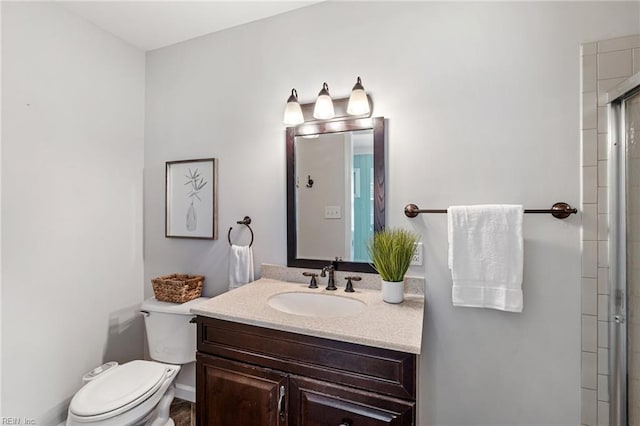 bathroom with toilet, vanity, and a shower with door