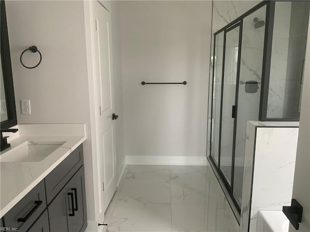 bathroom with marble finish floors, baseboards, a marble finish shower, and vanity