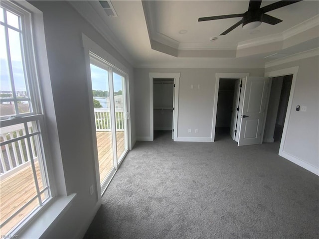 unfurnished bedroom featuring a tray ceiling, crown molding, carpet flooring, baseboards, and access to exterior