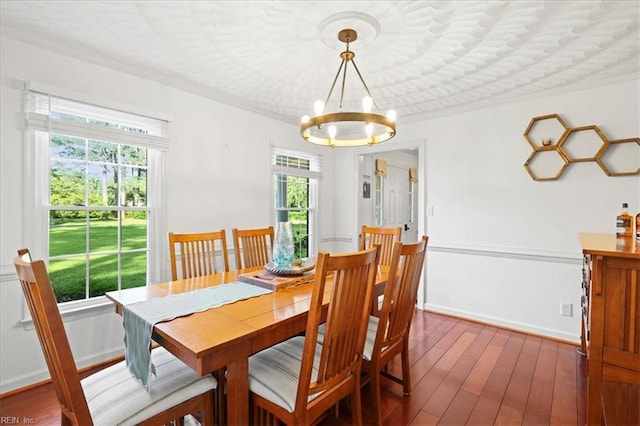 dining area featuring a chandelier, crown molding, and dark wood-style flooring