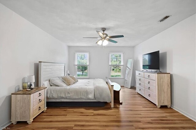 bedroom featuring light wood-type flooring, baseboards, and a ceiling fan