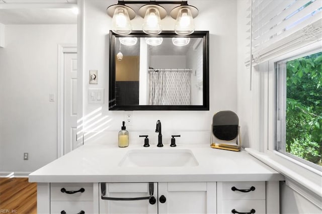 bathroom with healthy amount of natural light, vanity, and wood finished floors