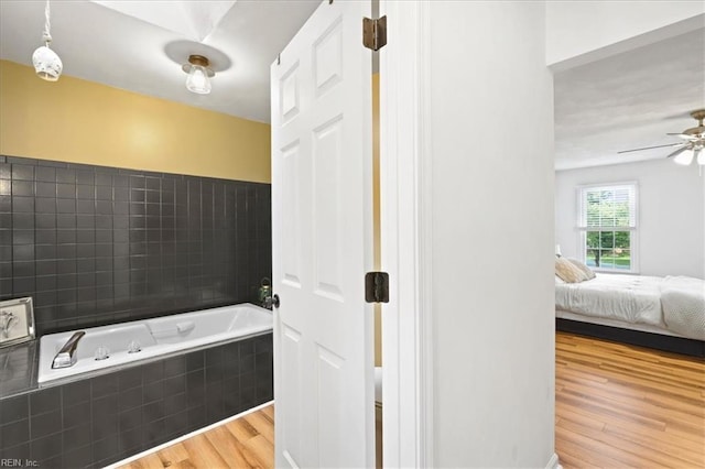 ensuite bathroom featuring wood finished floors, a bath, and ceiling fan
