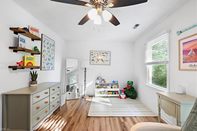 recreation room featuring light wood finished floors, ceiling fan, and baseboards