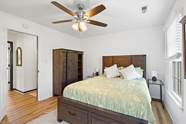 bedroom featuring light wood finished floors, multiple windows, and baseboards