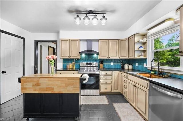 kitchen with appliances with stainless steel finishes, wall chimney range hood, a sink, and backsplash