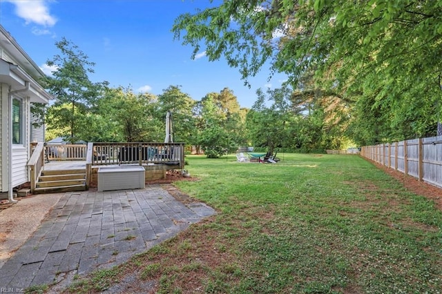 view of yard featuring a patio, a wooden deck, and view of scattered trees