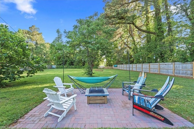 view of patio featuring an outdoor fire pit and view of wooded area