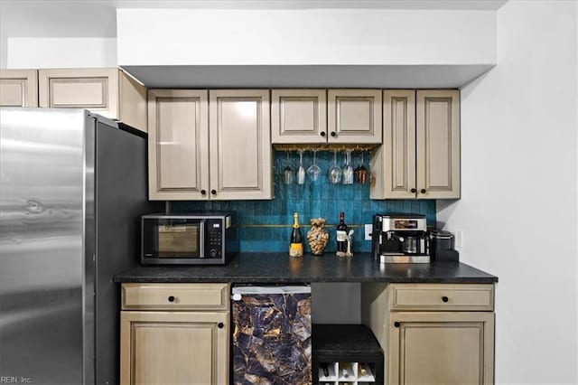 kitchen featuring appliances with stainless steel finishes, backsplash, dark countertops, and cream cabinetry