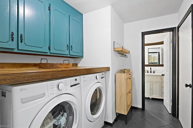 washroom featuring washer and clothes dryer, dark tile patterned floors, and cabinet space