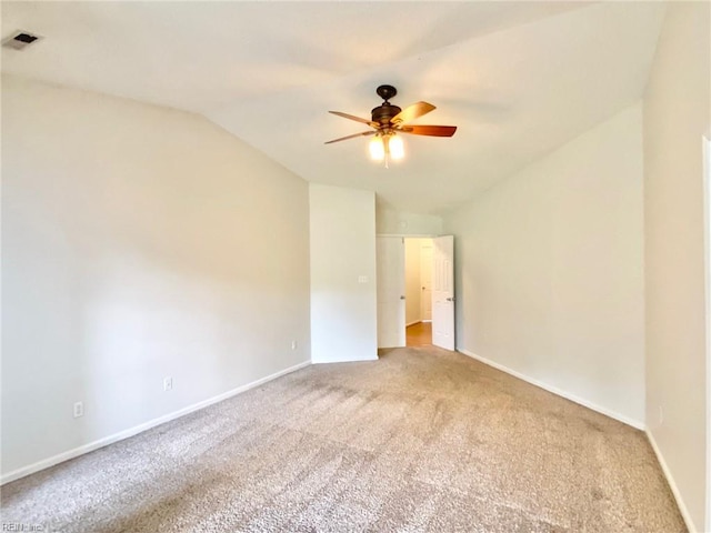 spare room with vaulted ceiling, light colored carpet, a ceiling fan, and baseboards