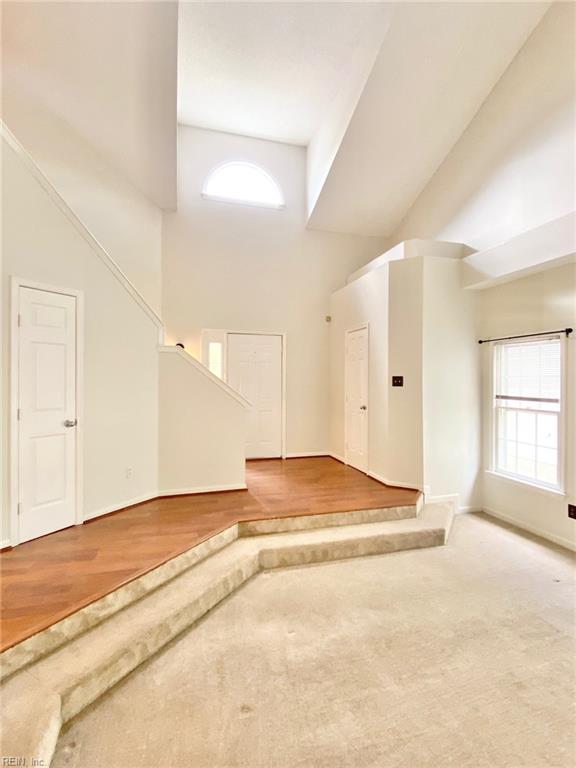 additional living space with a high ceiling, wood finished floors, and baseboards