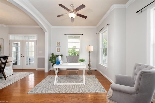 office space with wood finished floors, crown molding, arched walkways, ceiling fan, and baseboards