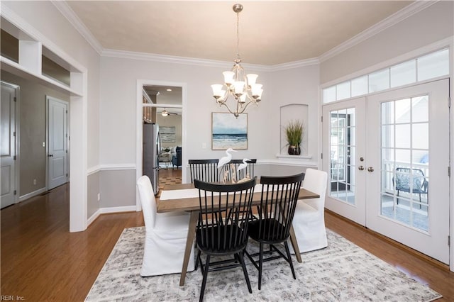 dining area with wood finished floors, ornamental molding, french doors, a chandelier, and baseboards