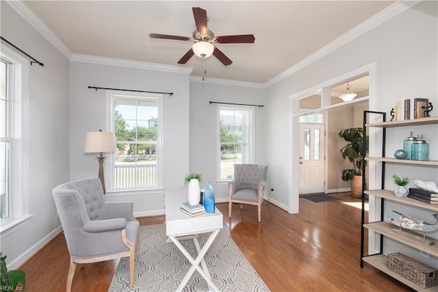 sitting room featuring wood finished floors, a ceiling fan, crown molding, and baseboards