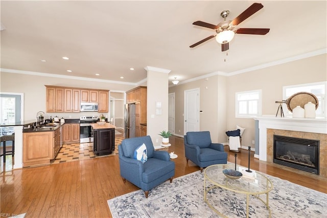 living area with light wood finished floors, a ceiling fan, plenty of natural light, recessed lighting, and ornamental molding