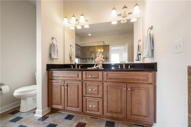 full bathroom featuring toilet, baseboards, a shower stall, double vanity, and stone finish flooring