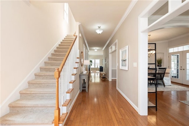 entrance foyer with stairway, crown molding, wood finished floors, baseboards, and french doors