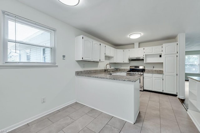 kitchen featuring stainless steel gas range, under cabinet range hood, a peninsula, white cabinetry, and a sink