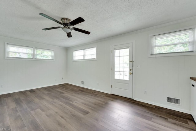 entryway featuring a textured ceiling, wood finished floors, ceiling fan, crown molding, and baseboards