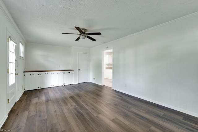 empty room featuring ceiling fan, dark wood-type flooring, a textured ceiling, baseboards, and crown molding