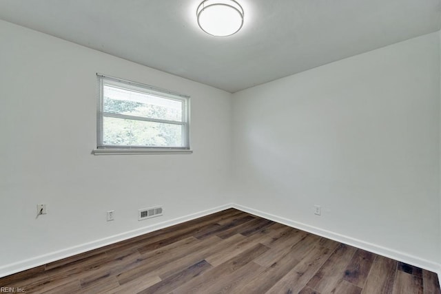 empty room featuring baseboards and dark wood finished floors