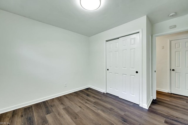 unfurnished bedroom with baseboards and dark wood-style floors