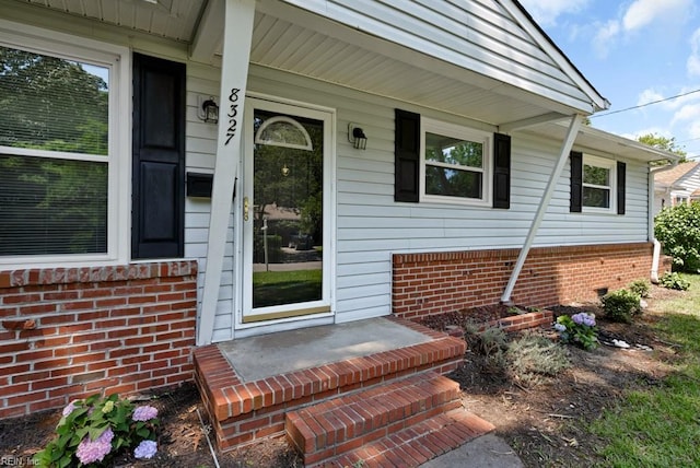 doorway to property featuring covered porch and brick siding