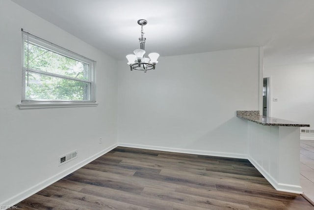 unfurnished dining area with a chandelier, dark wood-type flooring, and baseboards