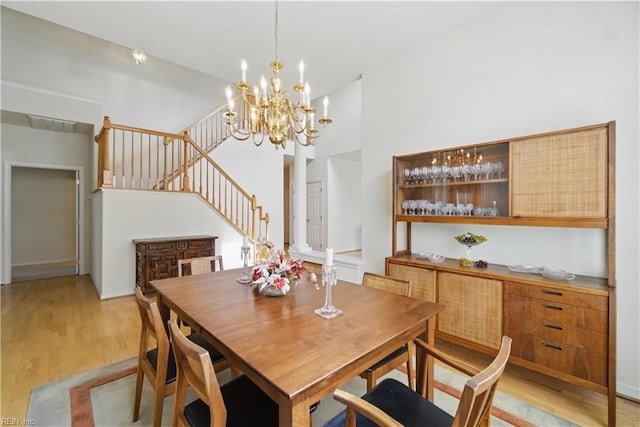 dining room with stairs, light wood-style floors, and a chandelier