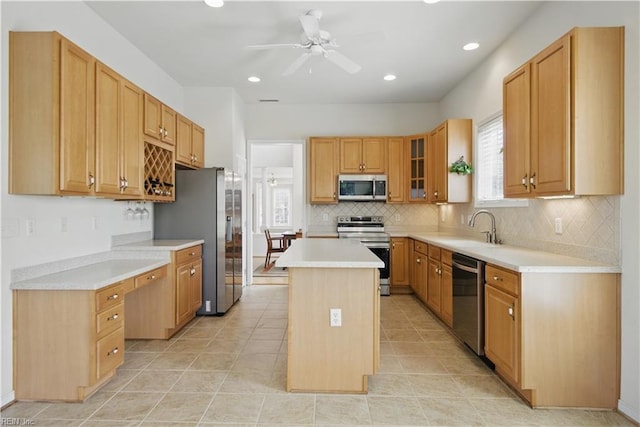kitchen with appliances with stainless steel finishes, a kitchen island, a ceiling fan, a sink, and decorative backsplash