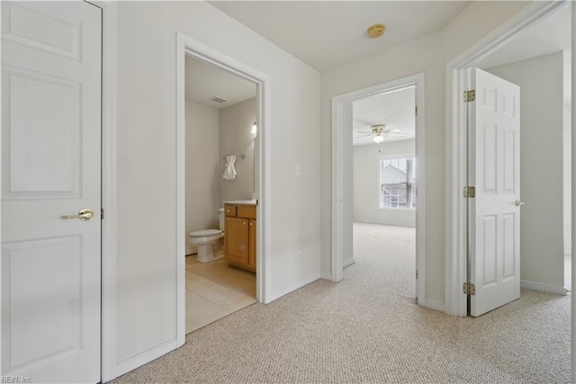 hallway featuring light carpet and baseboards