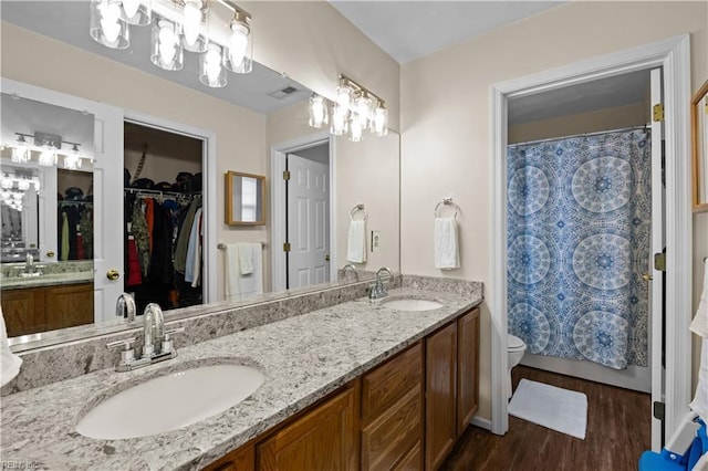 1309 W 25th St, Norfolk, VA 23508 - bathroom with wood finished floors, double vanity, toilet, a walk in closet, and curtained shower
