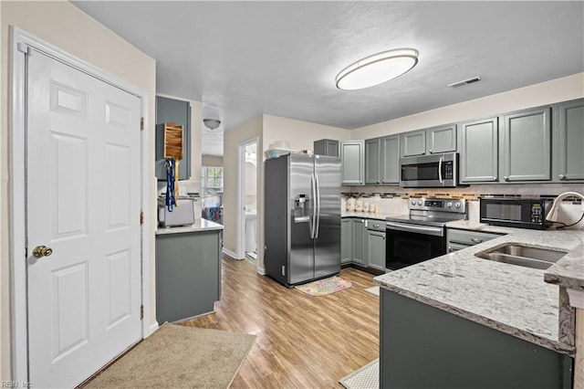1309 W 25th St, Norfolk, VA 23508 - kitchen with appliances with stainless steel finishes, gray cabinetry, a sink, decorative backsplash, and light stone counters