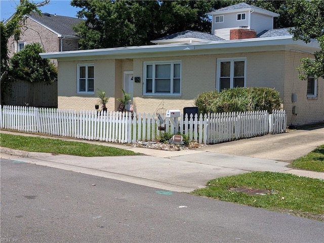 view of front facade with brick siding, a chimney, and a fenced front yard