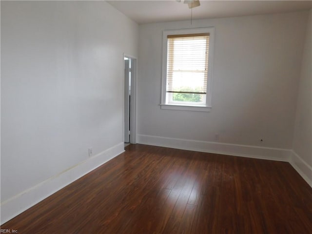 unfurnished room with baseboards and dark wood-style flooring