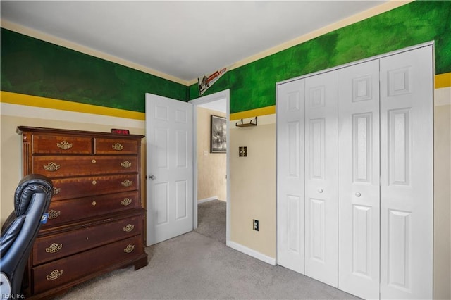 carpeted bedroom with a closet and baseboards