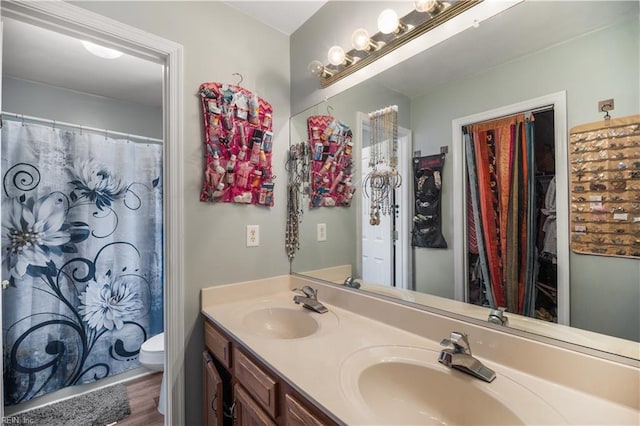 bathroom with double vanity, toilet, wood finished floors, and curtained shower
