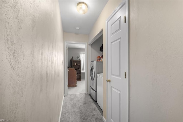 hallway featuring washer and dryer and light carpet
