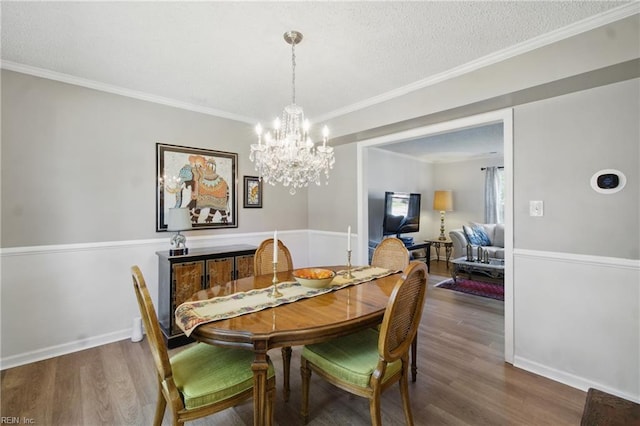 dining area with wood finished floors, a chandelier, baseboards, crown molding, and a textured ceiling