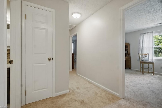 hall featuring carpet flooring, a textured ceiling, and baseboards