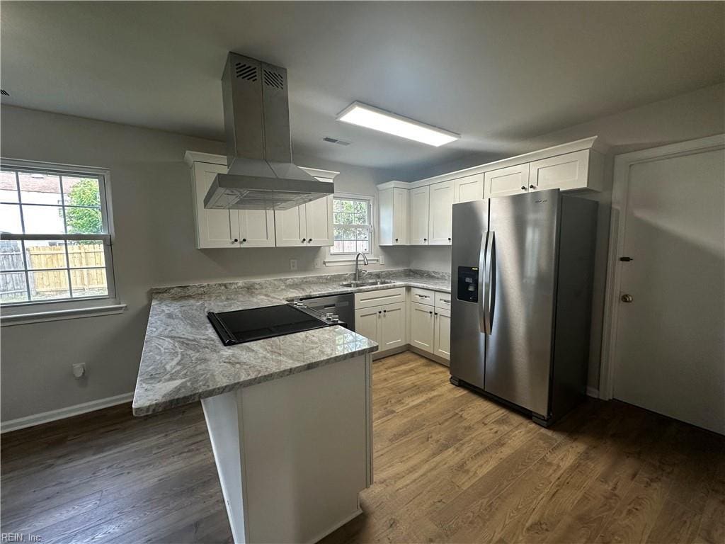 kitchen featuring stainless steel refrigerator with ice dispenser, island exhaust hood, a sink, a peninsula, and white cabinets