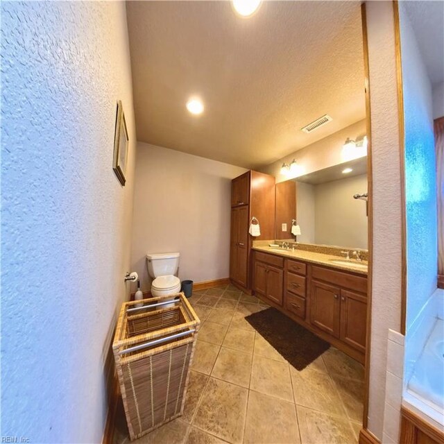 2390 Sandfiddler Rd, Corolla, NC 27927 - bathroom featuring a textured wall, tile patterned floors, double vanity, baseboards, and toilet