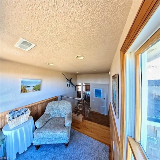 2390 Sandfiddler Rd, Corolla, NC 27927 - sitting room featuring a textured ceiling, wood finished floors, an upstairs landing, and plenty of natural light
