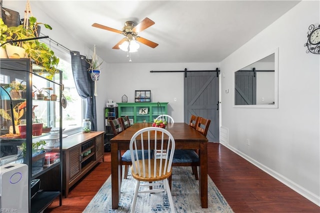 dining room featuring a barn door, wood finished floors, baseboards, and a ceiling fan