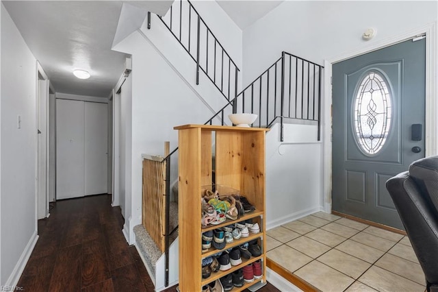 entryway with stairs, wood finished floors, and baseboards