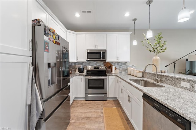 kitchen featuring stainless steel appliances, a sink, white cabinetry, backsplash, and recessed lighting