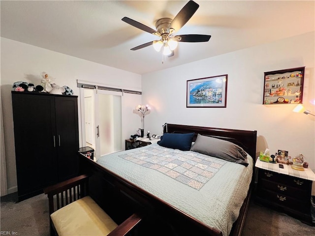 bedroom featuring dark colored carpet, a barn door, a closet, and ceiling fan