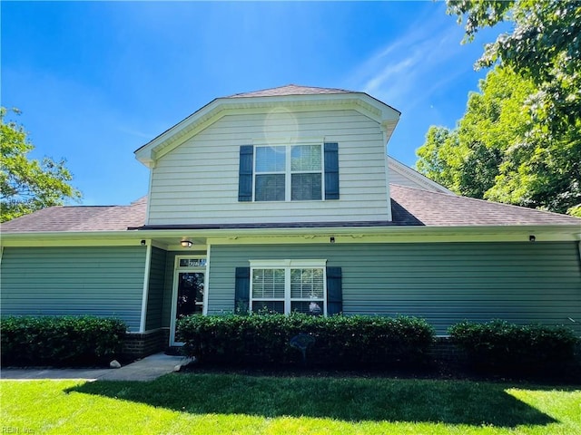 view of front facade featuring a front lawn and a shingled roof
